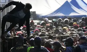 Seorang migran asal Malawi melompati barikade saat polisi mengatur antrean warga yang akan dideportasi di sebuah pusat penampungan sementara di Durban, Afrika Selatan, Kamis (18/6/2026). (Dok. AP Photo/Themba Hadebe, Arsip)