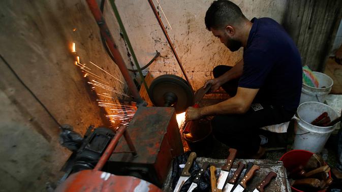 Seorang pria Palestina menajamkan pisau yang akan digunakan untuk menyembelih hewan kurban dalam perayaan Idul Adha di sebuah lokakarya di Kota Gaza, 28 Juli 2020. Idul Adha merupakan salah satu tanggal penting dalam kalender Islam. (AP Photo/Hatem Moussa)