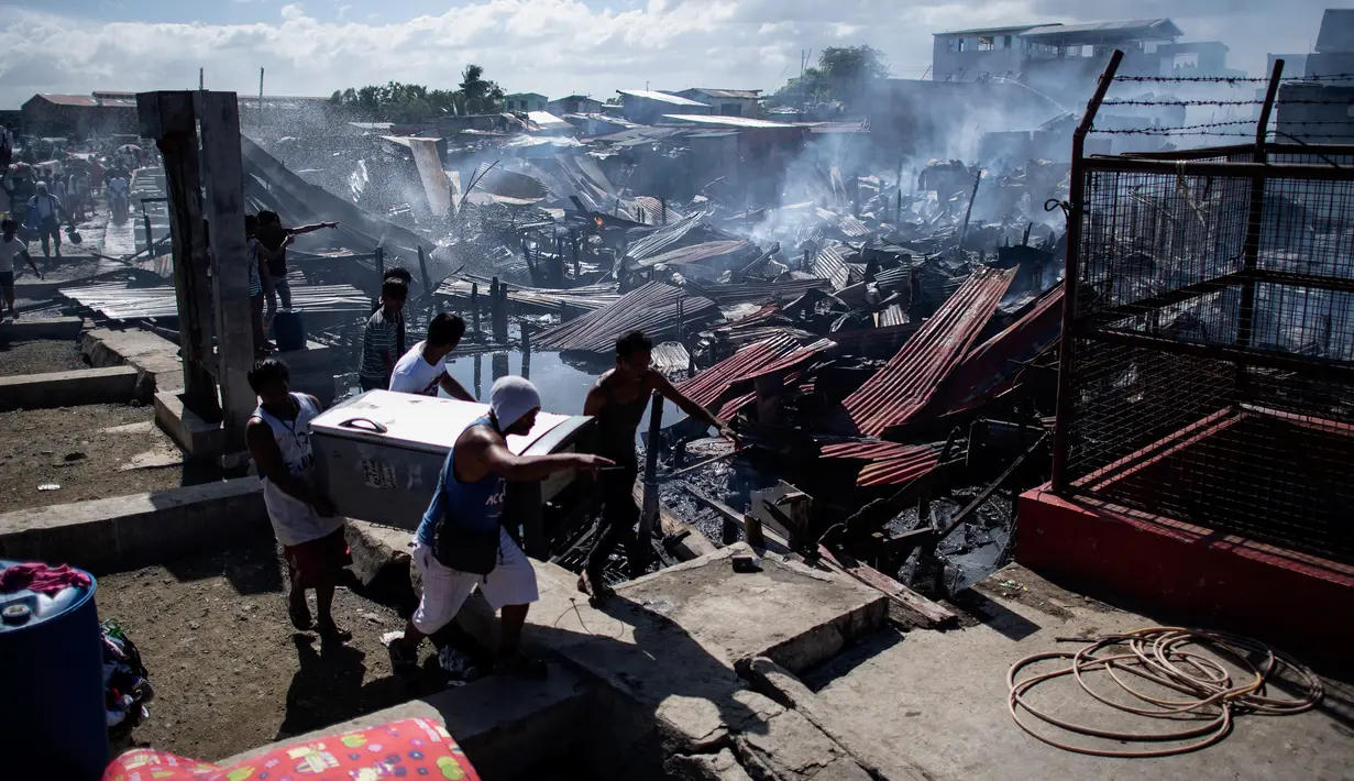 Sejumlah warga membawa barang miliknya saat rumah-rumah mereka hangus terbakar di sebuah daerah kumuh di Navotas, Manila (8/11). Dilaporkan sekitar 150 keluarga terkena dampak kebakaran tersebut. (AFP Photo/Noel Celis)