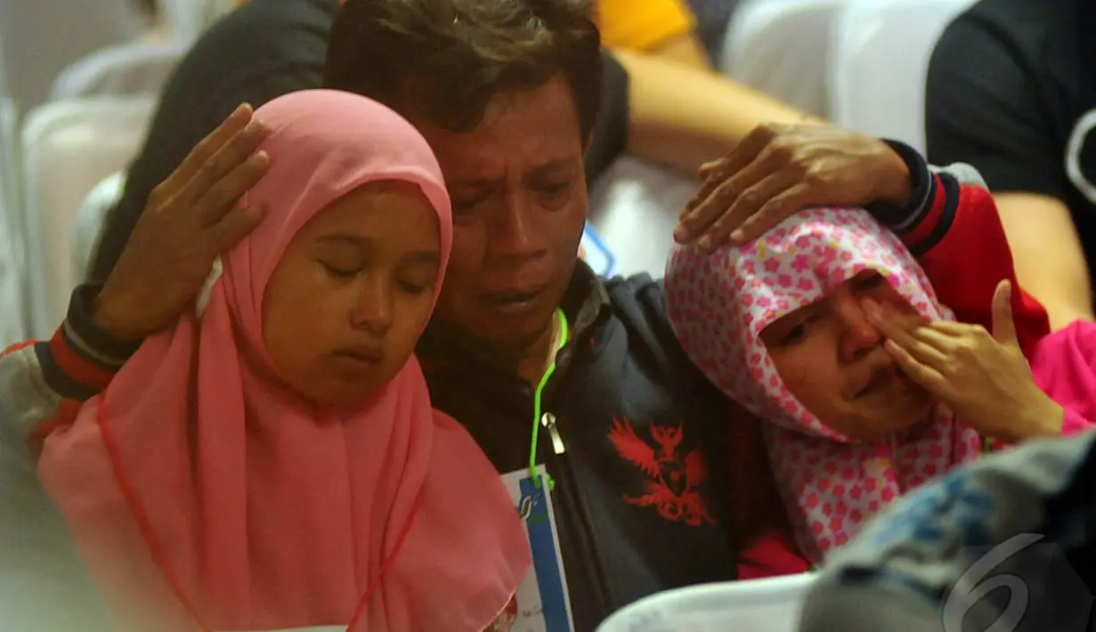 Seorang pria terlihat merangkul keluarganya setelah mendengar kabar penemuan pesawat AirAsia QZ8501, Surabaya, Selasa (30/12/2014). (Liputan6.com/Johan Tallo)