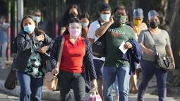Orang-orang yang memakai masker berjalan di samping jalan di kota Quezon, Filipina, Senin (17/1/2022). Orang-orang yang belum menerima vaksin COVID-19 dilarang naik transportasi publik di ibu kota Manila mulai Senin menyusul lonjakan kasus covid varian omicron. (AP Photo/Aaron Favila)