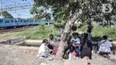 Warga berteduh di bawah pohon saat berunjuk rasa di depan gerbang Kampung Susun Bayam, Jakarta Utara, Senin (21/11/2022). Berdasarkan kesepakatan, seharusnya warga sudah mulai bisa menempati hunian pada 20 November 2022 kemarin. (merdeka.com/Iqbal S. Nugroho)