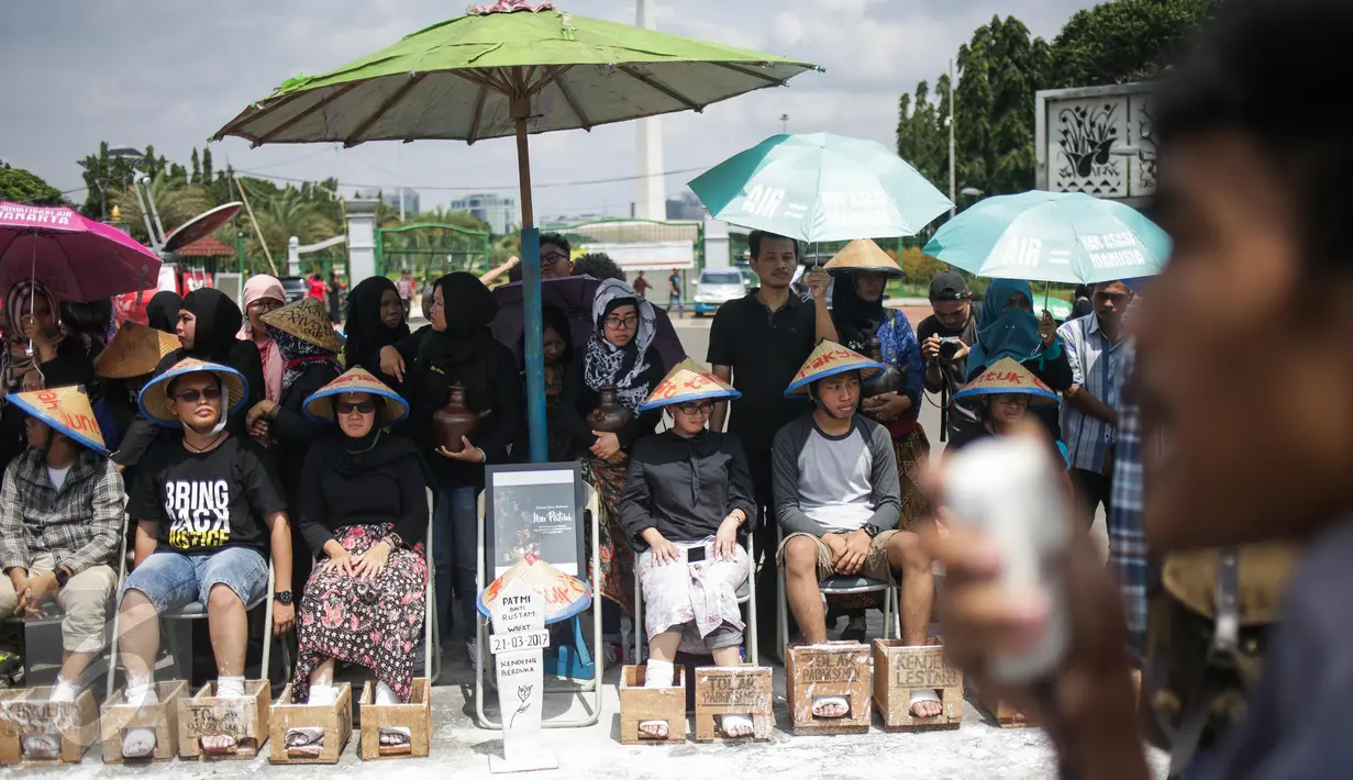 Delapan aktivis dari sejumlah lembaga swadaya masyarakat mengecor kaki mereka di depan Istana Merdeka, Jakarta, Rabu (22/3). Aksi itu merupakan lanjutan dari protes pembangunan pabrik semen di Pegunungan Kendeng, Jawa Tengah. (Liputan6.com/Faizal Fanani)