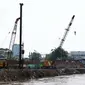 Alat berat dikerahkan untuk memasang pasak di bantaran Kali Ciliwung, Bukit Duri, Jakarta (1/11). Pemasangan tiang pancang untuk sheet pile di kali tersebut ditargetkan hingga 2000 meter dan selesai akhir Desember 2016. (Liputan6.com/Gempur M Surya)