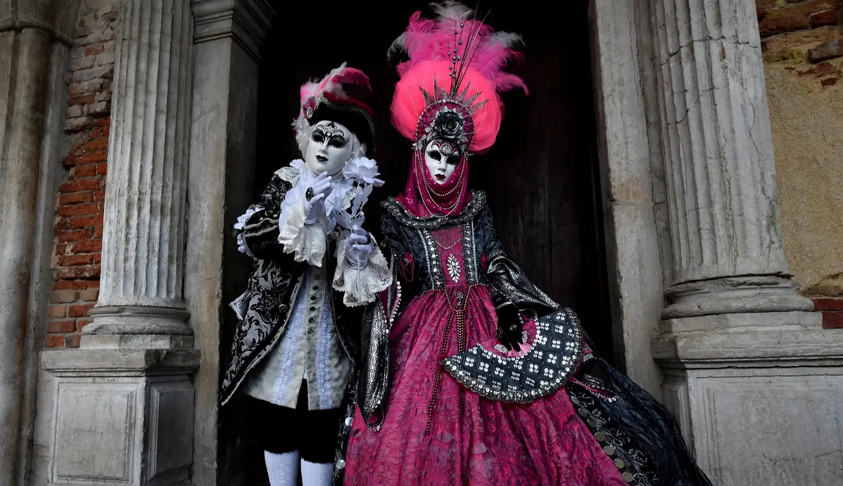 Dua orang peserta mengenakan kostum dan topeng berpose untuk difoto saat berpartisipasi dalam Karnaval Venesia di Italia (27/1). Beberapa jenis topeng yang dikenal antara lain Bauta dan Volto atau Larva. (AFP Photo/Filippo Monteforte)