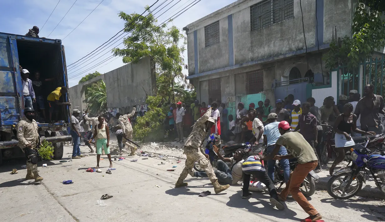 Polisi menghadapi warga yang untuk sementara menyalip sebuah truk yang penuh dengan pasokan bantuan, di Les Cayes, Haiti, Jumat (20/8/2021).  Bantuan swasta dan kiriman dari pemerintah AS dan lainnya tiba di semenanjung barat daya negara itu. dilanda. (AP Photo/Fernando Llano)