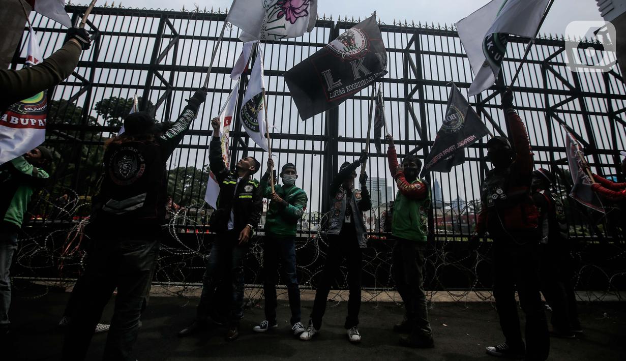 Pengemudi ojek online yang tergabung dalam Koalisi Ojol Nasional menggelar aksi di depan Gedung DPR RI, Jakarta, Senin (29/8/2022). Ratusan pengemudi ojek online tersebut menuntut beberapa hal di antaranya payung hukum dan legalitas profesi ojek online serta revisi potongan komisi pendapatan mitra. (Liputan6.com/Faizal Fanani)