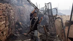 Warga mengambil besi dari puing-puing bangunan menyusul kebakaran yang melanda permukiman Cantagallo di Lima, Peru, Jumat (4/11). Pejabat setempat mengatakan, ada 46 orang yang sempat dirawat akibat terlalu banyak menghirup asap. (REUTERS/Guadalupe Pardo)