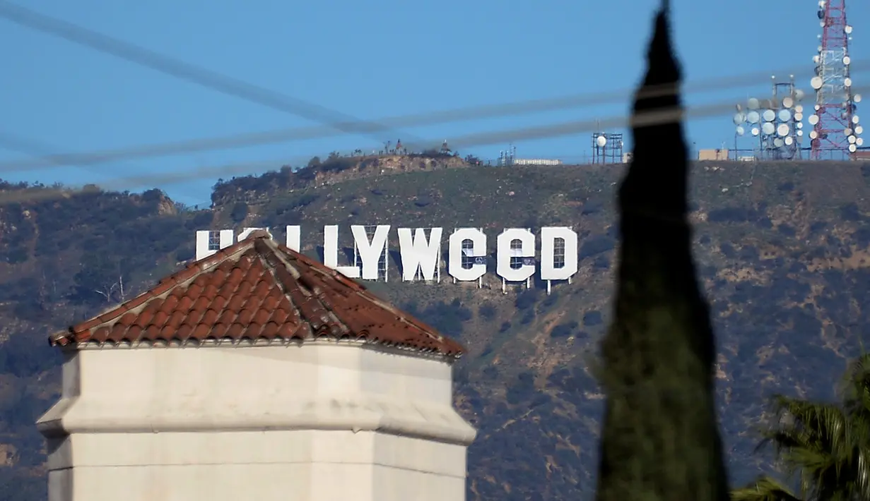 Tanda ikonik Hollywood yang diubah menjadi Hollyweed  di Hollywood Hills, Los Angeles, Minggu (1/1). Pelaku vandalisme , yang diduga seorang pria, menggunakan semacam terpal untuk mengubah huruf 'O' menjadi 'e'. (REUTERS/Kevork Djansezian)