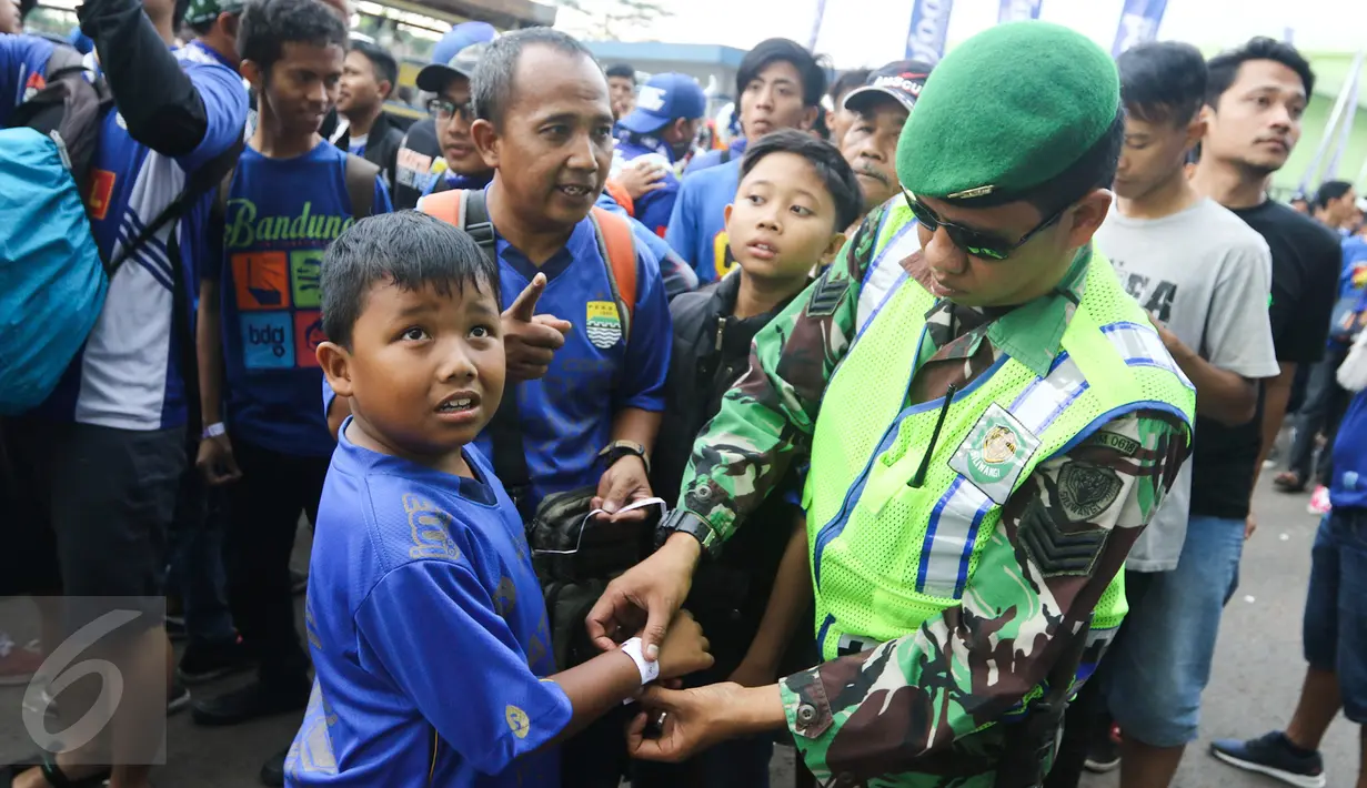 Petugas keamanan memasangkan penonton gelang tiket masuk pertandingan di Stadion Gelora Bandung Lautan Api (GLBA), Jawa Barat, Sabtu (15/4). Bobotoh penasaran ingin melihat aksi Essien dan Cole di laga perdana Maung Bandung. (Liputan6.com/Yoppy Renato)