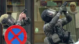 Dua Polisi antiteror Belgia bersenjata saat menggerebek sebuah apartemen di Molenbeek, Brussel, Belgia, (8/3). Wilayah ini memang dihuni oleh imigran-imigran asal Afrika Utara. (REUTERS/VTM)