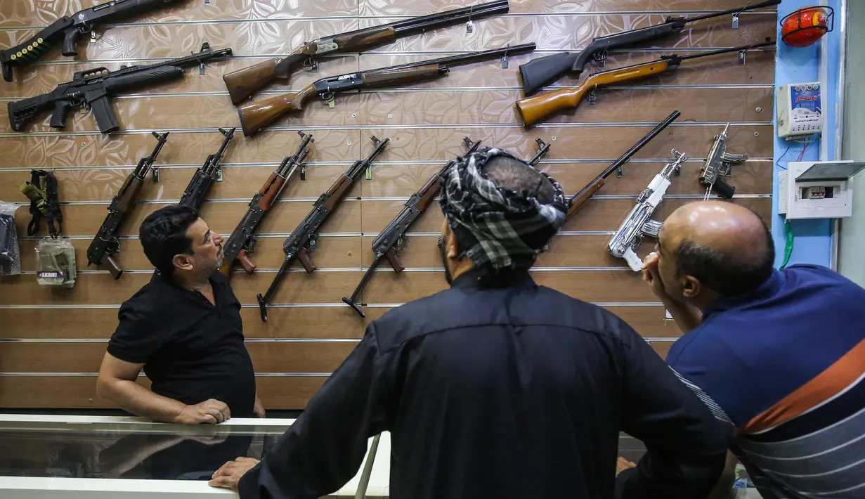 Seorang penjual, Abu Hauraa menunjukkan kepada klien berbagai macam senapan di toko senjata berlisensi miliknya di Baghdad, 24 September 2018. Setelah pelegalan senjata api untuk sipil, permintaan akan senjata api semakin meningkat. (AFP/AHMAD AL-RUBAYE)