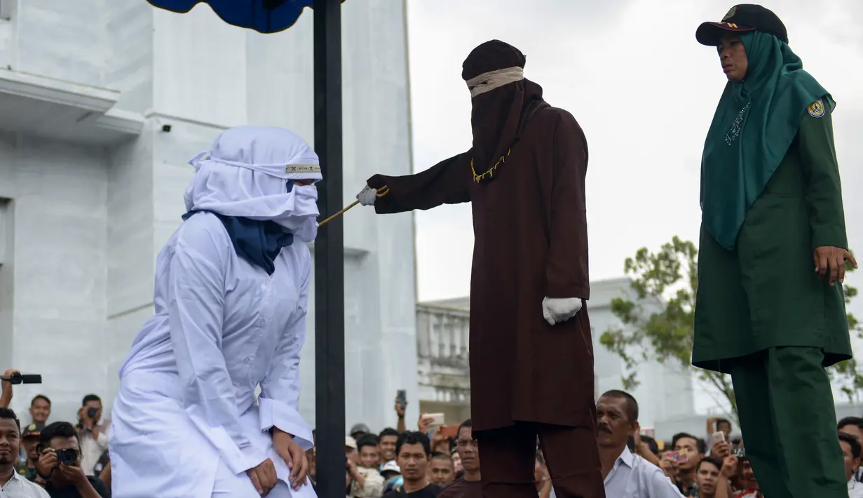 Petugas syariah mencambuk pekerja seks komersial (PSK) online di halaman Masjid Jamik Lueng Bata, Banda Aceh, Aceh, Jumat (20/4). Petugas syariah melakukan hukum cambuk terhadap dua PSK online. (CHAIDEER MAHYUDDIN / AFP)