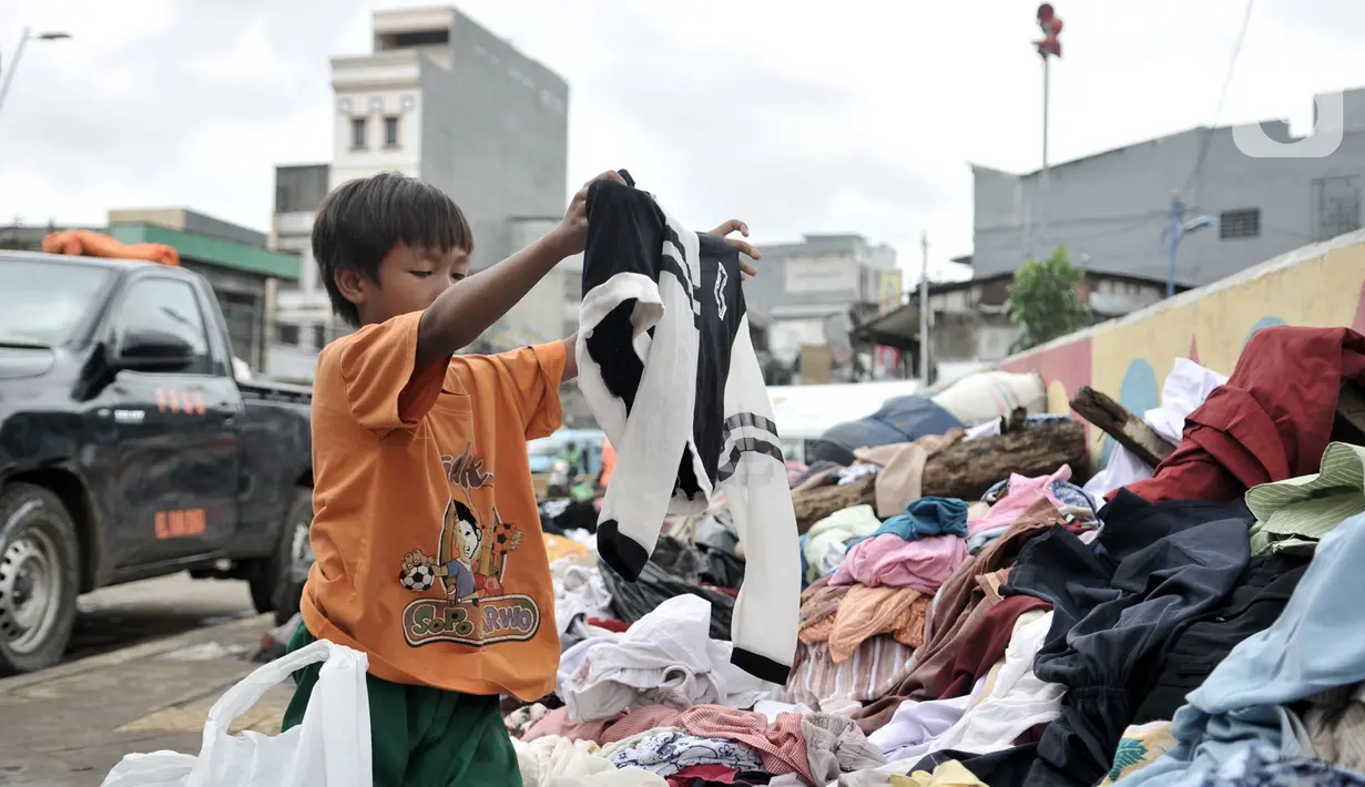 Seorang anak memilih pakaian sumbangan yang ditempatkan di pinggir Kali Ciliwung, Kampung Pulo, Jakarta Timur, Senin (6/1/2020). Banjir menyebabkan ratusan warga di Kampung Pulo kehilangan pakaian akibat rusak dan hanyut. (merdeka.com/Iqbal S. Nugroho)