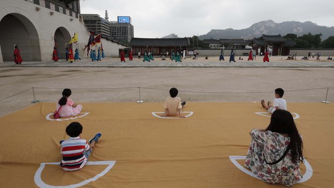 Pengunjung menonton sambil menjaga jarak sosial selama upacara berlakunya kembali pergantian Pengawal Kerajaan di Istana Gyeongbok, salah satu landmark terkenal Korea Selatan, di Seoul, Korea Selatan, Jumat (31/7/2020). (AP Photo/Lee Jin-man)