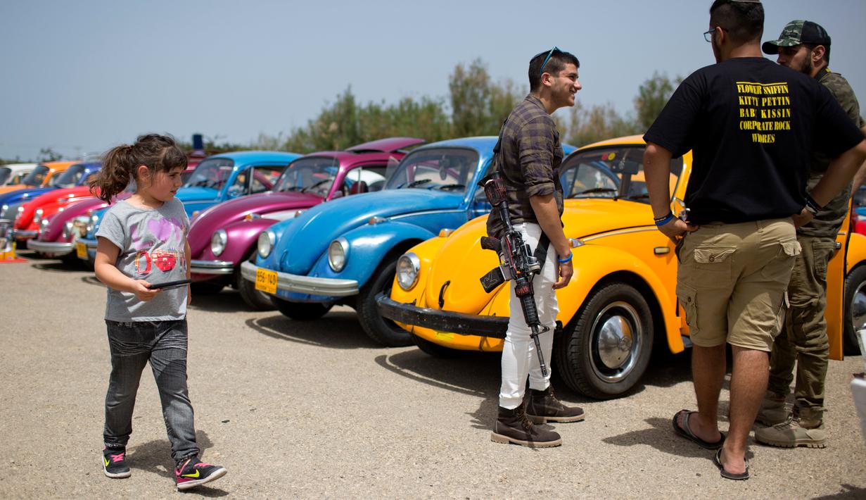 Seorang anak berjalan diantara mobil Volkswagen Beetle dalam ajang pertemuan tahunan "Beetle club" di Yakum, Israel tengah (21/4). Dalam pertemuan ini mereka memamerkan mobil Volkswagen Beetle dengan aneka modifikasi. (AP Photo / Oded Balilty)