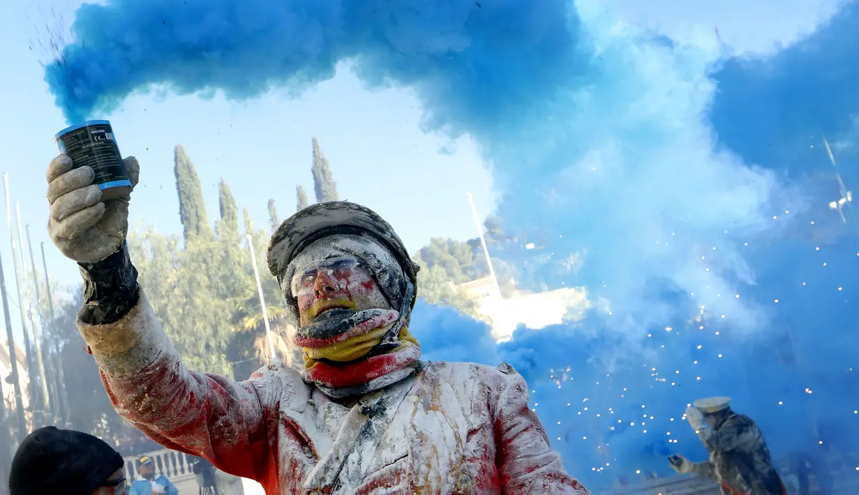 Seorang peserta menyalakan kembang api saat mengikuti festival Els Enfarinats di Kota Ibi, Spanyol, Sabtu (28/12/2019). Dalam festival yang sudah berlangsung selama 200 tahun ini para peserta bertempur menggunakan tepung, telur, dan petasan. (AP Photo/Alberto Saiz)