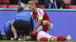 Gelandang Denmark, Christian Eriksen tergeletak di tanah setelah pingsan pada laga Denmark vs Finlandia di Grup B Euro 2020 di Parken Stadium, Copenhagen, Sabtu (12/6/2021). Laga dihentikan jelang berakhirnya babak pertama setelah Christian Eriksen pingsan. (Friedemann Vogel/Pool via AP)