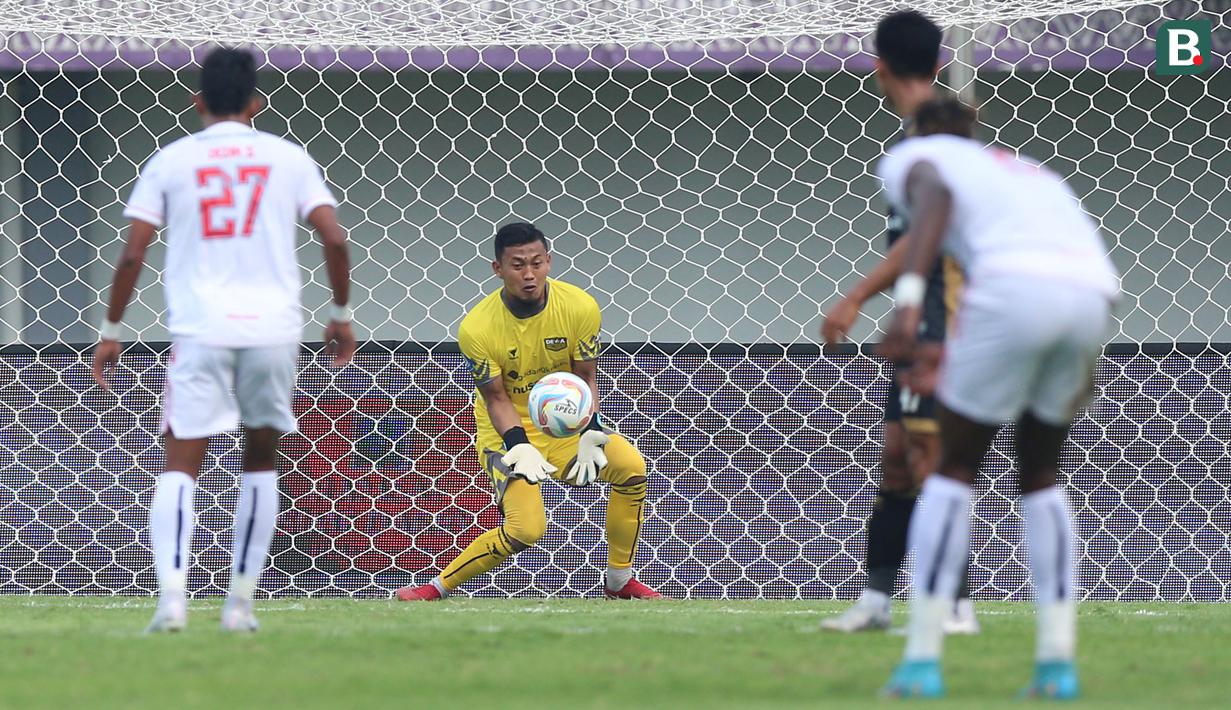 Kiper Dewa United FC, M Natshir Fadhil Mahbuby berusaha menghalau bola tendangan pemain Arema FC, Ichaka Diarra pada laga pekan pertama BRI Liga 1 2023/2024 antara Dewa United melawan Arema FC di Stadion Indomilk, Tangerang, Minggu (2/7/2023). (Bola.com/Bagaskara Lazuardi)