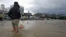 Seorang warga berjalan melewati banjir di Gangneung, Korea Selatan, Kamis (3/9/2020). Lebih dari 2.200 orang dievakuasi ke tempat penampungan sementara. (Lee Hae-yong/Yonhap via AP)
