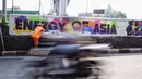 Kendaraan melintasi petugas PSSU yang sedang menyelesaikan mural bertema Asian Games di kawasan Tanjung Barat, Jakarta, Kamis (31/5). Mural itu dibuat untuk sosialisasi dan mendukung perhelatan Asian Games pada Agustus 2018. (Liputan6.com/Faizal Fanani)