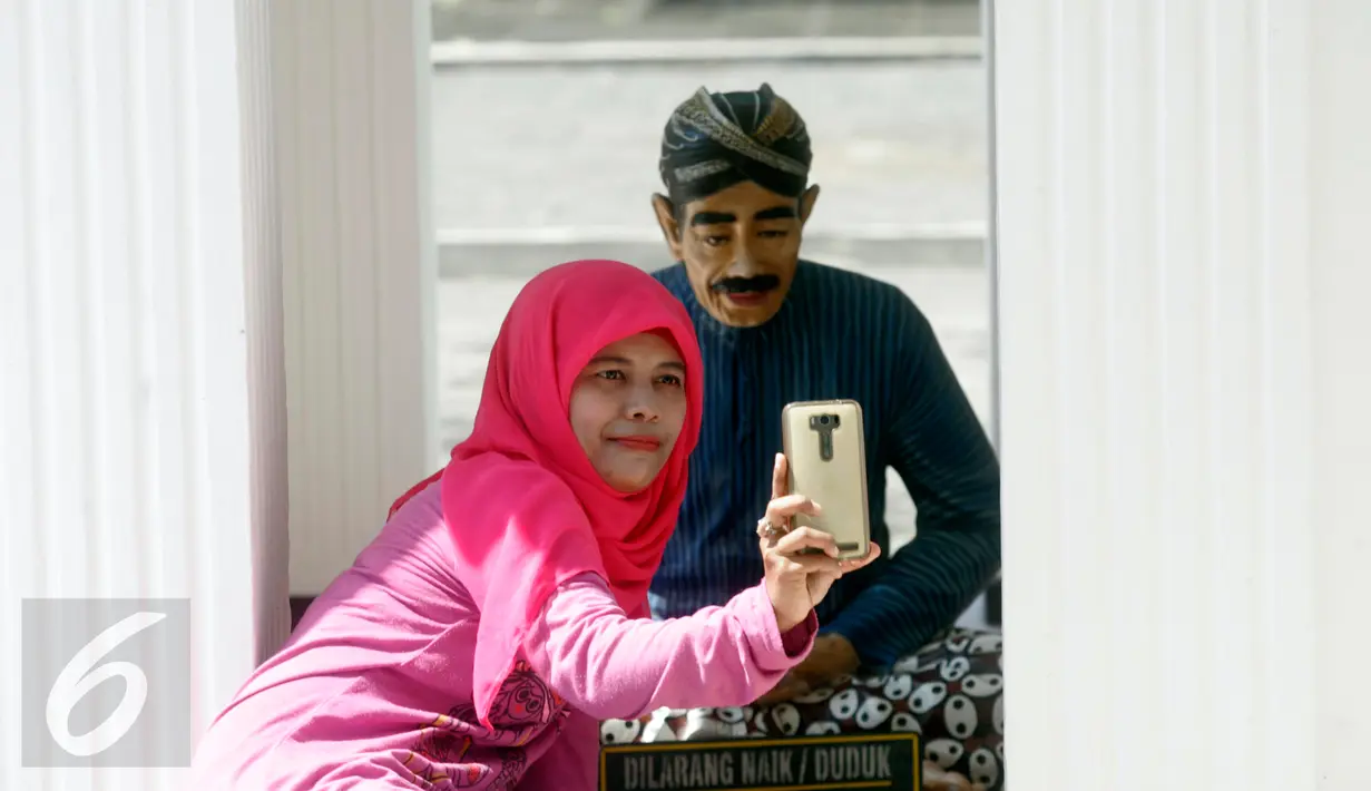 Wisatawan berselfie dengan patung di keraton kesultanan Yogyakarta,(10/7).Kunjungan wisata mengalami lonjakan menjelang liburan akhir lebaran .(Boy Harjanto)
