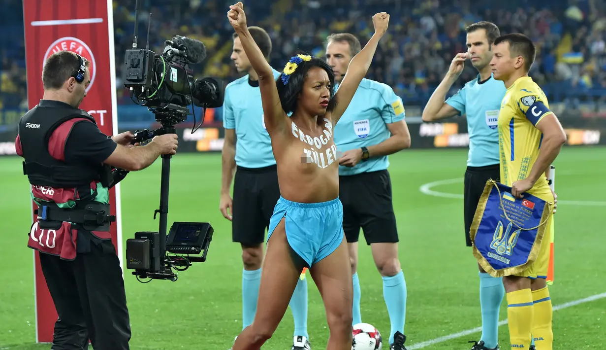 Seorang wanita dari aktivis Femen bertelanjang dada berpose didalam lapangan sebelum pertandingan sepak bola kualifikasi Piala Dunia 2018 antara Ukraina dan Turki di Kharkiv (2/9). (AFP Photo/Sergei Supinsky)