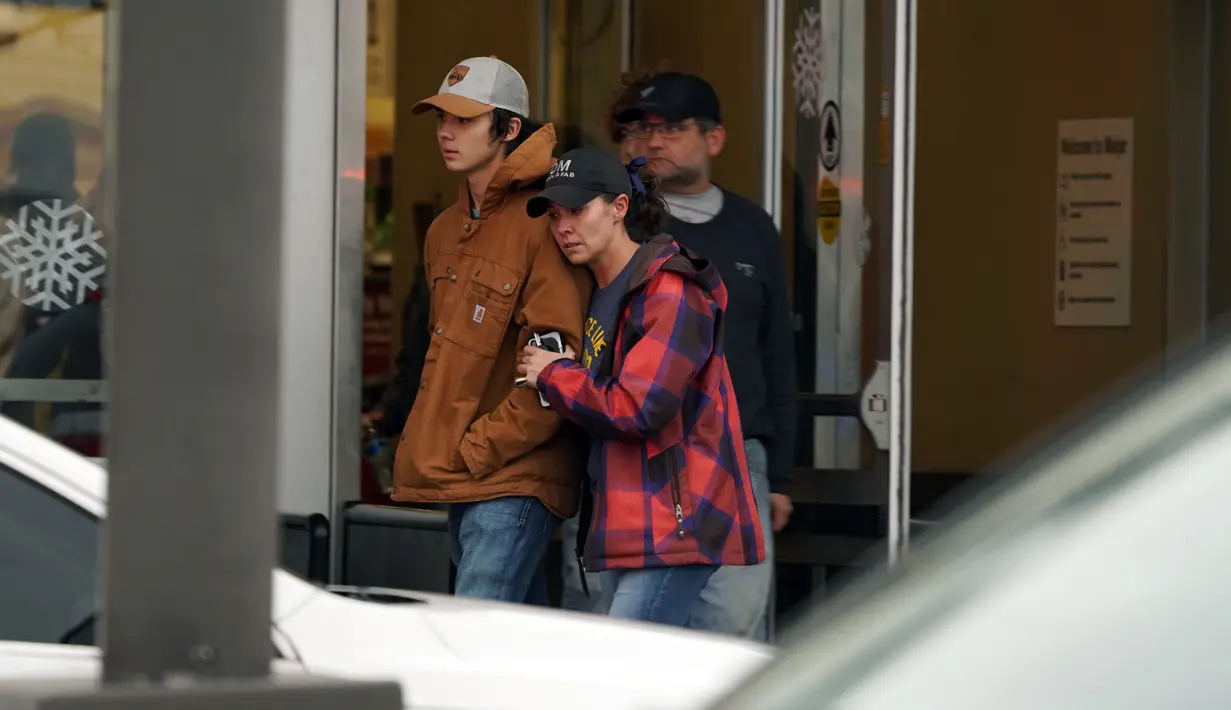 Orang tua memeluk ananya ketika yang lain datang untuk menjemput siswa dari toko Meijer di Oxford, Michigan, menyusul situasi penembak aktif di Oxford High School di Oxford, Michigan (30/11/2021). (Ryan Garza/Detroit Free Press via AP)