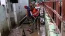 Petugas Damkar PB bersama PPSU membersihkan lumpur sisa banjir di salah satu gang di kawasan Rawajati, Jakarta, Sabtu (27/4). Banjir akibat luapan air sungai Ciliwung sempat melanda kawasan ini pada Jumat (26/4). (Liputan6.com/Helmi Fithriansyah)