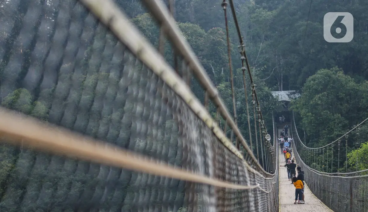 Pengunjung melintasi Jembatan Gantung Situ Gunung di Sukabumi, Minggu (20/9/2020). Dari rata-rata 2.500 pengunjung tiap harinya kini hanya di bawah 1.000 pelancong per hari akibat merebaknya pandemi Covid-19 serta adanya penerapan PSBB. (merdeka.com/Iqbal S. Nugroho)