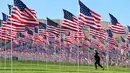 Seorang wanita berjalan melewati pameran bendera AS untuk peringatan 20 tahun serangan 9/11 di Pepperdine University di Malibu, Rabu (8/9/2021). Selama 14 tahun, universitas itu memperingati tragedi 11 September 2001 dengan mengibarkan sekitar 3.000 bendera Amerika. (Frederic J. BROWN/AFP)