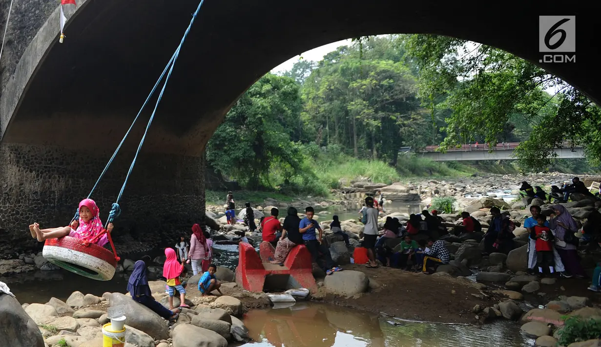 Seorang anak bermain ayunan di kolong jembatan Sempur, Bogor (16/9). Musim kemarau yang menyebabkan debit Sungai Ciliwung menyusut drastis dimanfaatkan warga Bogor dan sekitarnya untuk berwisata murah dan gratis di aliran sungai. (Merdeka.com/Arie Basuki)