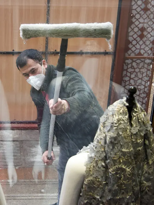 Seorang pria membersihkan jendela toko di Urumqi, Daerah Otonomi Xinjiang, China barat laut, Rabu (4/3/2020). Urumqi mengampanyekan sanitasi di seluruh kota guna mencegah penyebaran virus corona (COVID-19). (Xinhua/Ding Lei)