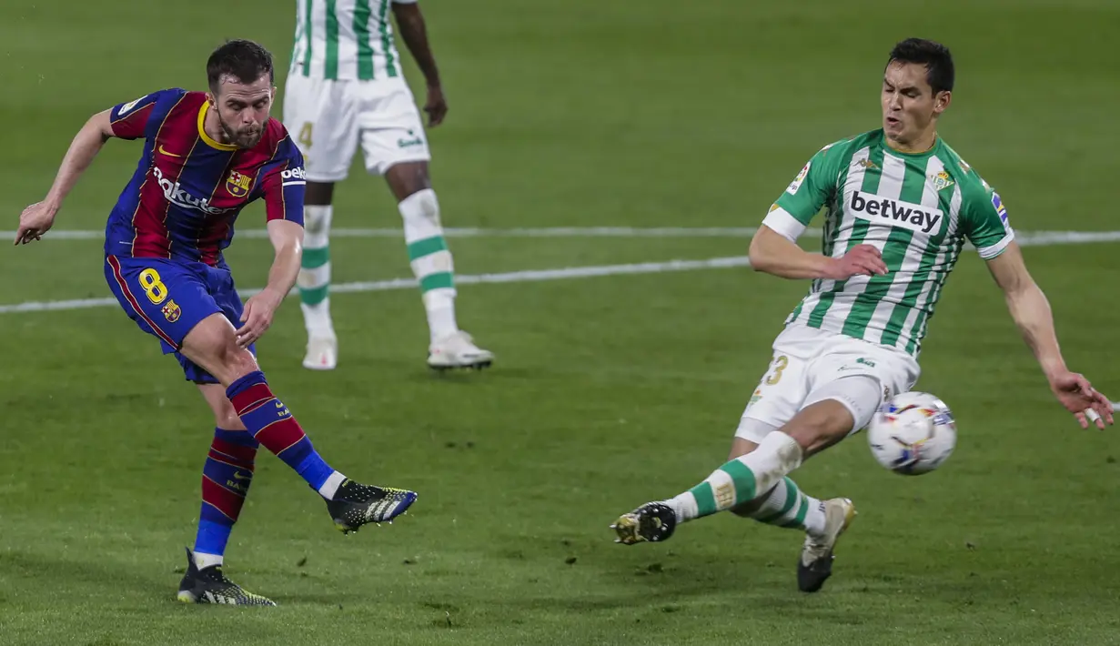 Gelandang Barcelona, Miralem Pjanic menembak bola dari kawalan pemain Real Betis, Aissa Mandi pada lanjutan La Liga Spanyol di stadion Benito Villamarin di Seville, Spanyol, Senin (8/2/2021).  Kemenangan ini membuat Barcelona berada di posisi dua pada klasemen. (AP Photo/Miguel Morenatti)