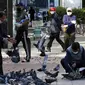 Orang-orang yang memakai masker untuk membantu melindungi dari penyebaran virus corona COVID-19 memberi makan burung merpati di sebuah jalan di Goyang, Korea Selatan, Rabu (11/11/2020). (AP Photo/Ahn Young-joon)
