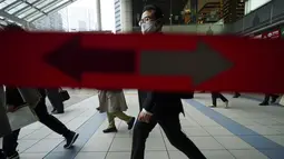 Penumpang kereta mengenakan masker berjalan selama jam sibuk di Stasiun Shinagawa di Tokyo, Senin (22/3/2021). Perdana Menteri Jepang Yoshihide Suga pada Senin mencabut keadaan darurat virus corona di Tokyo dan tiga prefektur lainnya yang tersisa. (AP Photo/Eugene Hoshiko)
