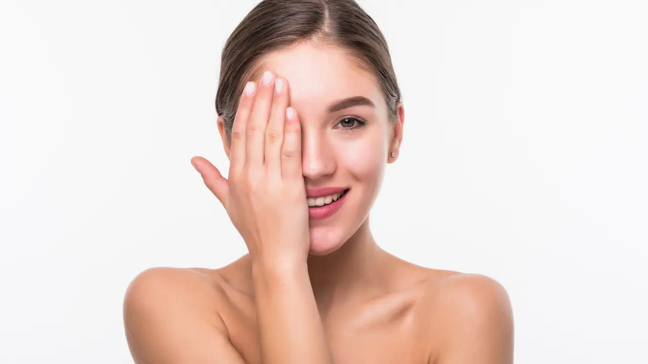 Seorang perempuan dengan rambut digulung tersenyum sambil menutup sebagian wajahnya dengan tangan (Foto Dok: Freepik/diana.grytsku)
