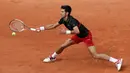 Petenis Serbia, Novak Djokovic melakukan servis ke arah petenis Italia Marco Cecchinato pada perempatfinal Prancis Terbuka 2018 di stadion Roland Garros, Selasa (5/6). Djokovic tumbang 3-6, 6-7, 6-1, dan 6-7. (AP/Alessandra Tarantino)