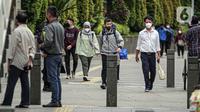Para pekerja yang mengenakan masker berjalan kaki setelah meninggalkan perkantorannya di Jakarta, Rabu (2/2/2022). Kasus harian COVID-19 di Indonesia pada hari ini bertambah 17.895 jadi 94.109 kasus aktif, membuat total kasus sejak awal pandemi mencapai 4.387.286 kasus. (Liputan6.com/Faizal Fanani)