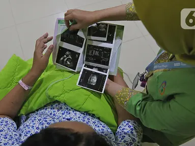 Suster menunjukkan hasil USG kandungan dari Regina (43) yang akan menjalani proses persalinan di RSUD Pasar Minggu, Jakarta, Kamis (20/2/2020). Bayi perempuan dari pasangan Regina dan Andre (47) lahir secara sesar di tanggal 20 bulan 02 tahun 2020 atau 20-02-2020. (Liputan6.com/Herman Zakharia)