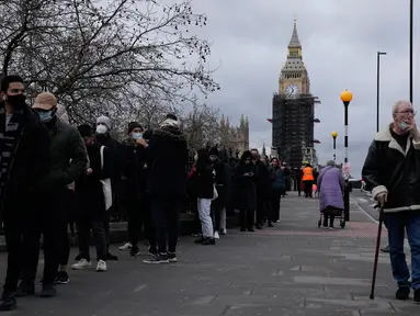 Orang-orang antre untuk suntikan vaksin booster Covid-19 di Rumah Sakit St Thomas, London, Senin (13/12/2021). Antrean panjang terbentuk di pusat vaksinasi di Inggris ketika pemerintah mendorong agar semua orang dewasa mendapatkan vaksin booster untuk cegah penyebaran Omicron. (AP Photo/Matt Dunham)