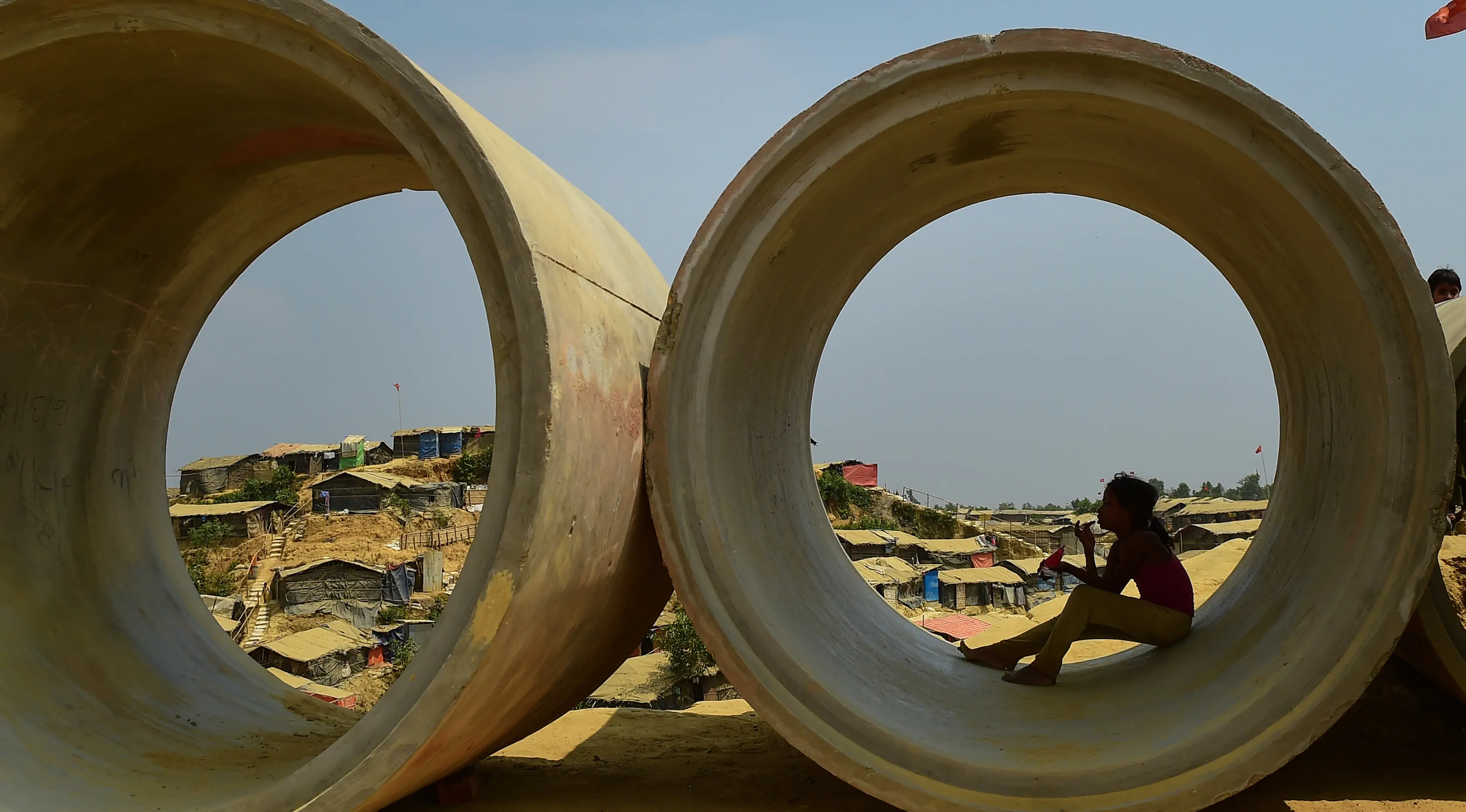 Seorang bocah pengungsi Rohingya duduk di dalam pipa limbah di kamp pengungsi Kutupalong, Bangladesh (5/4). Pemerintah Bangladesh mengatakan akan memulai relokasi sekitar 100.000 pengungsi Rohingya. (AFP Photo/Munir Uz Zaman)