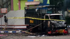 Seorang polisi memasang garis polisi di samping kendaraan yang dibakar di luar Stadion Kanjuruhan, Malang, Jawa Timur, Minggu (2/10/2022). Sebanyak 127 orang tewas ketika para penggemar yang marah menyerbu lapangan sepak bola setelah pertandingan antara Arema FC dan Persebaya Surabaya pada 1 Oktober 2022. (PUTRI/AFP)