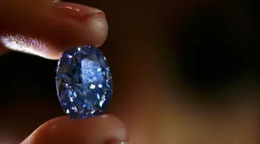 Seorang petugas memegang berlian biru 10,10 karat di rumah lelang sothbey, London, Inggris, Selasa (15/3). Diperkirakan harga berlian ini mencapai $ 35.000.000 atau 525 Miliar rupiah.  (REUTERS / Stefan Wermuth)