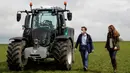 Duchess of Cambridge Kate Middleton (kanan) berjalan dengan petani Stewart Chapman setelah dia mengendarai traktor saat kunjungan dengan Pangeran William ke Manor Farm di Little Stainton, Durham, Inggris, Selasa (27/4/2021). (Owen Humphreys/POOL/AFP)