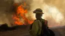Petugas melihat kebakaran hutan di Cherry Valley, California (1/8/2020). Hampir setiap tahun, California dilanda kebakaran besar-besaran yang menyebabkan polusi udara tinggi. (AP Photo/Ringo H.W. Chiu)