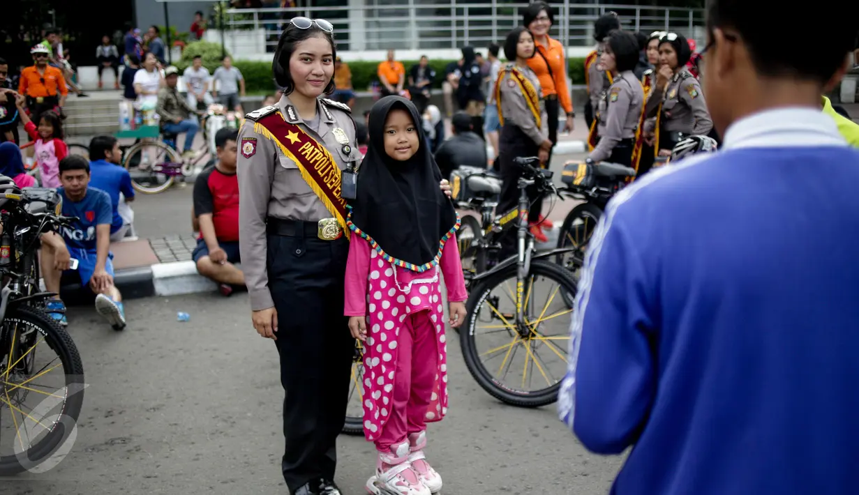 Seorang anak berfoto dengan polisi wanita (Polwan) dari kesatuan Samapta Bhayangkara (Sabhara) Polda Metro Jaya di kawasan Bundaran HI, Jakarta, Minggu (26/3). Polwan bersepeda ini memantau kelancaran car free day. (Liputan6.com/Faizal Fanani)