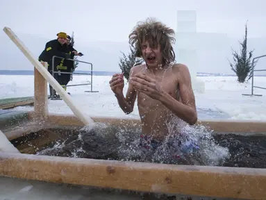 Seorang pria mandi di air dingin sungai Klyazma selama perayaan Epiphany tradisional saat suhu turun hingga sekitar -20 derajat di luar Moskow, Rusia (19/1/2021). Ribuan umat Kristen Ortodoks Rusia memperingati Hari Epiphany dengan berendam di kolam air es. (AP Photo/Alexander Zemlianichenko Jr)