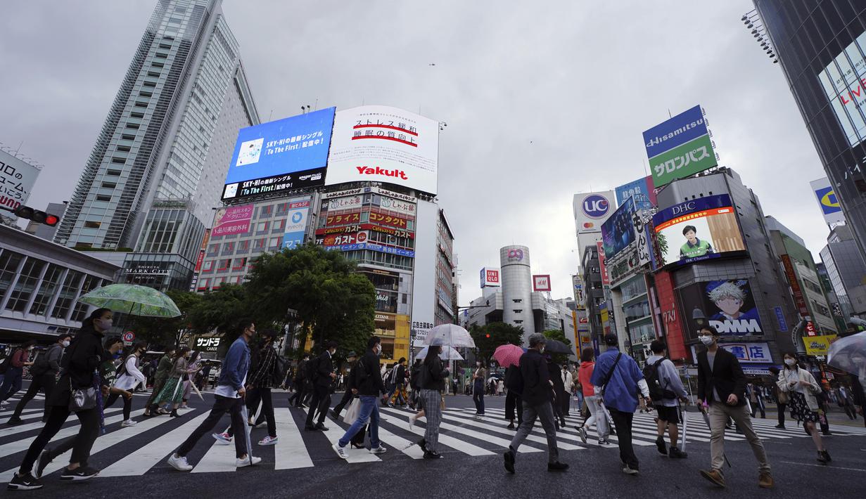 Orang-orang mengenakan masker untuk mencegah virus corona berjalan melintasi penyeberangan pejalan kaki pada awal liburan "Minggu Emas" Jepang di distrik Shibuya, Tokyo, Kamis (29/4/2021). Pemerintah Jepang meminta warga untuk tinggal di rumah selama "minggu emas". (AP Photo/Eugene Hoshiko)