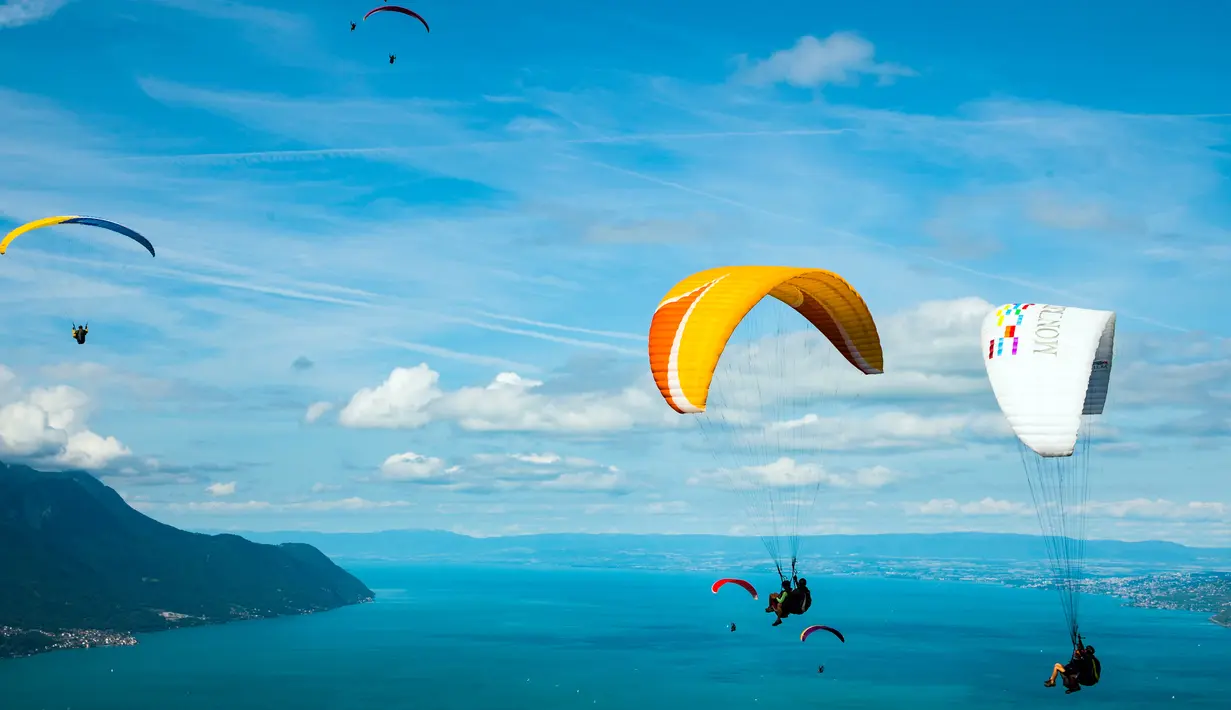 Sejumlah paraglider melakukan penerbangan menuju pendaratan "Acro Show" di atas Danau Jenewa di Villeneuve, Swiss (20/8). Paragliding adalah olahraga terbang bebas dengan menggunakan sayap kain (parasut). (Valentin Flauraud / Keystone via AP)